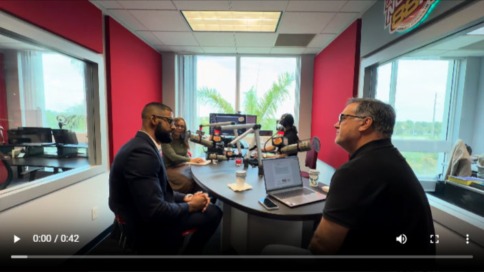 two men having a conversation in a studio with microphones on a table