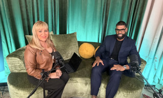 a woman and a man sitting on a green couch with microphones in front of themg